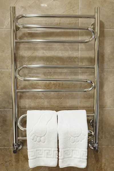 Modern heated towel rail on tiled bathroom wall