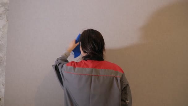 Женщина покрывает стены обоями — стоковое видео