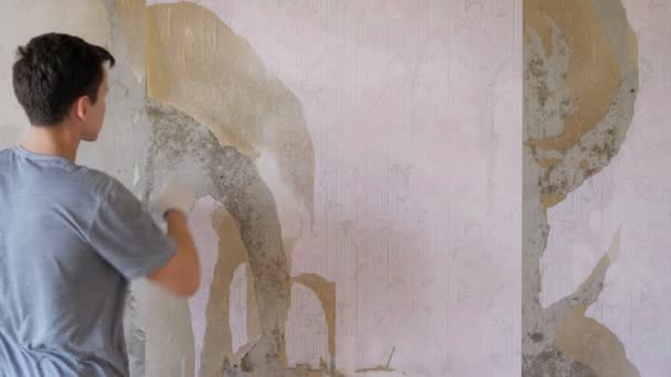 Homem arrancando papel de parede no quarto — Vídeo de Stock