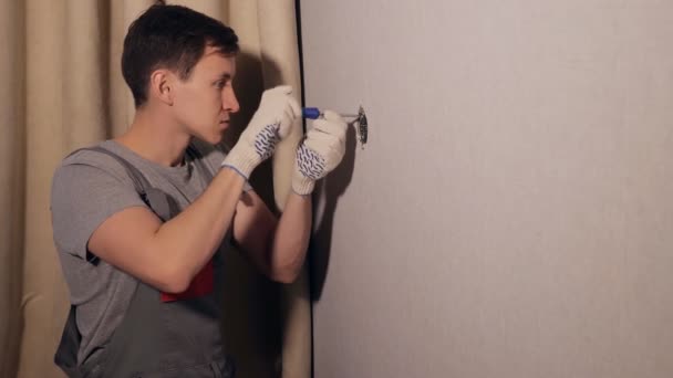 Человек устанавливает розетку на стену — стоковое видео