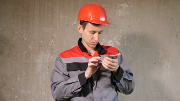 Contratista en hardhat usando el teléfono en el sitio — Vídeo de stock