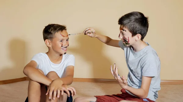 Lekfull pojkar måla ansikten med borstar — Stockfoto
