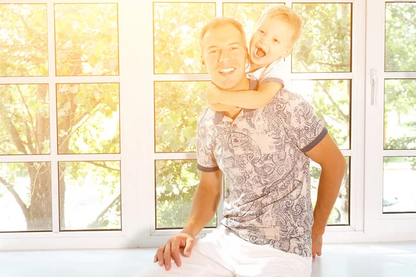 Sonriente niño abraza a papá en contra de la ventana — Foto de Stock