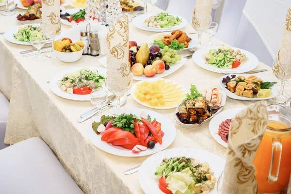 La mesa para invitados, servida con cubiertos y vajilla y cubierta con un mantel de oro — Foto de Stock