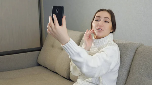 Cool kvinna i tröja tar en bild på sig själv med sin telefon — Stockfoto