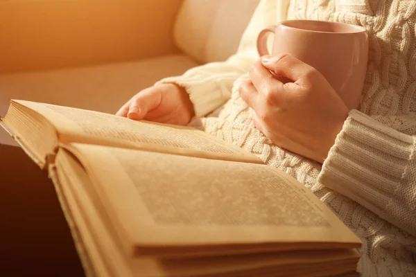 çay tutarak ve açık kitap okuma genç kadın