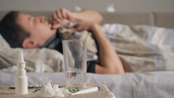 Лекарство и стакан воды рядом с больным парнем — стоковое видео