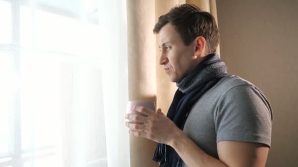 Sick man with hot drink near window — Stock Video