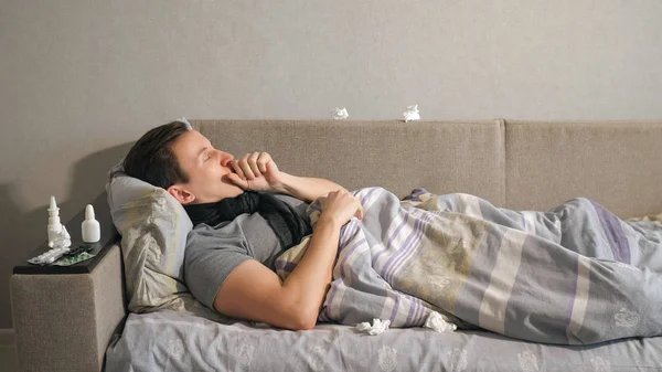 Hombre tosiendo acostado en un sofá — Foto de Stock
