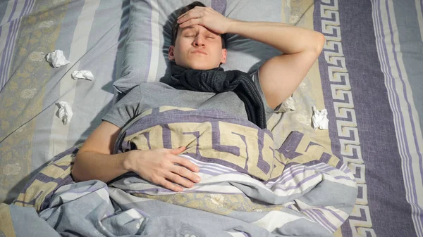 Больной человек касается головы на кровати — стоковое фото