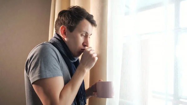 Varón enfermo con taza tosiendo cerca de la ventana — Foto de Stock