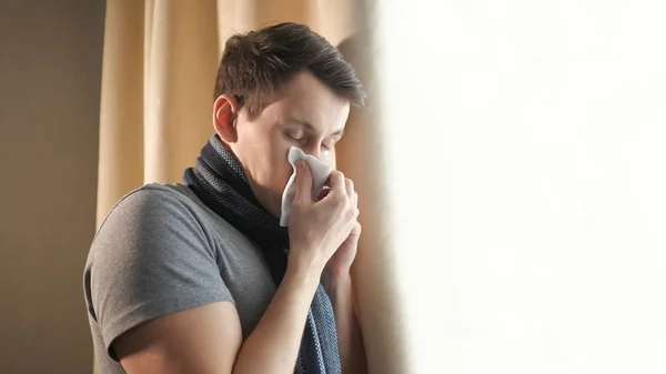 Hombre enfermo soplando nariz cerca de la ventana —  Fotos de Stock