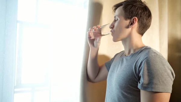 Hombre agua potable cerca de ventana — Foto de Stock