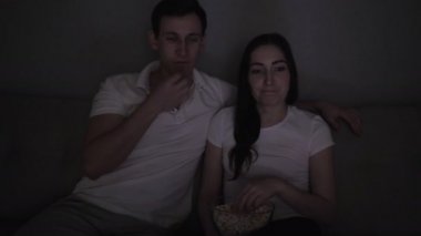 TV 'de film izleyen mutlu çift evdeki kanepede oturuyor..