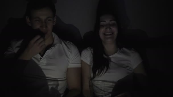 Glückliches Paar schaut sich einen Film im Fernsehen an und sitzt zu Hause auf einer Couch. — Stockvideo
