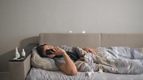 Unhealthy man in bed next to his medications in his home calling on the phone. — Stock Video