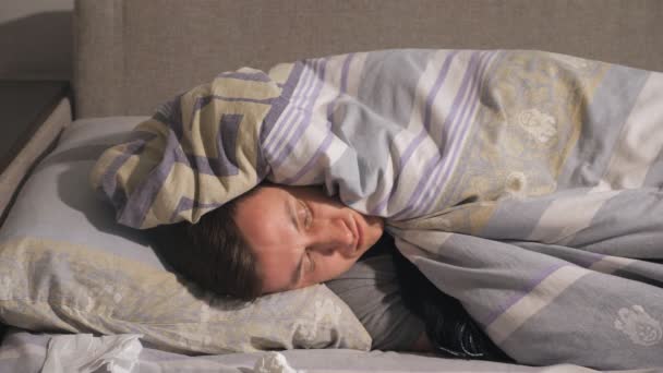 Nemocný muž ležící pod dekou
