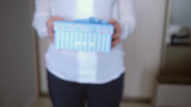 Ung kvinna ger en gåva på suddig bakgrund — Stockvideo