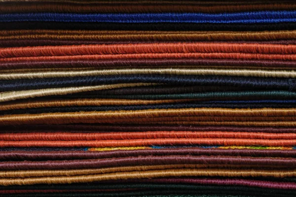 Tapetes macios multicoloridos variados deitados em uma pilha na loja moderna — Fotografia de Stock