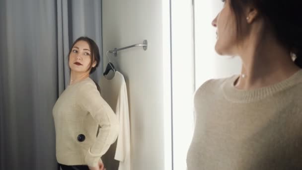 Mooie vrouw meet de kleren in een paskamer — Stockvideo