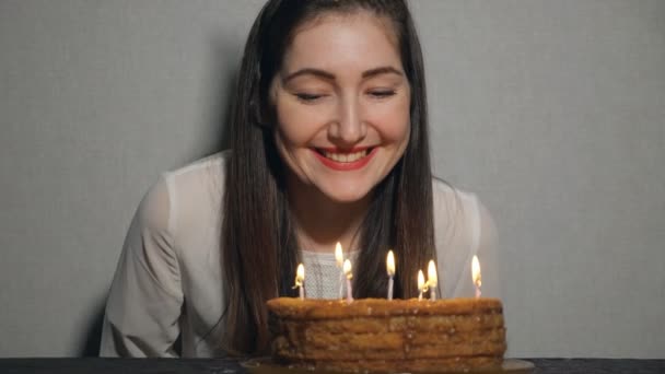 Счастливая эмоциональная девушка задувает свечи во время празднования своего дня рождения и аплодирует — стоковое видео