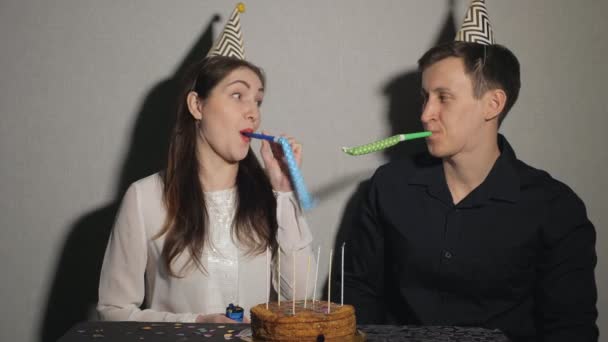 Young couple celebrates a holiday, he sits alone at a table with a cake and a candles — Stock Video