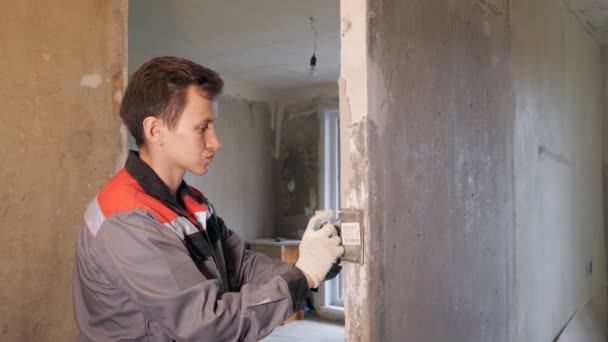 Мужчина оштукатуривает бетонную стену в квартире — стоковое видео