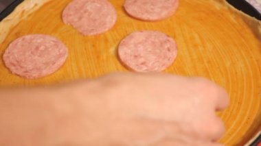 Bir genç pizza makinesi pizza Restoran mutfağında hazırlar. Aşçı sosis parçaları bir pizza koyar. Yakın çekim.