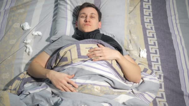 Chory człowiek z grypa i Katar wytrzeć nos chusteczką podczas leżenia na kanapie w domu — Wideo stockowe