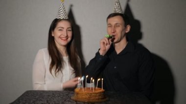 Çift gülümseyen parti üfleyiciler ile oynarken bir tatil kutluyor