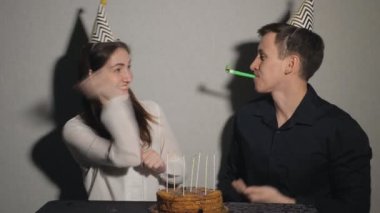 Sevimli küçük kız ve adam bir tatil kutluyor, bir pasta ve parti üfleyiciler ile oynarken bir mum bir masada oturuyor