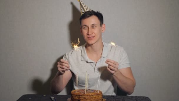 Solitario feliz hombre con pastel y una vela sosteniendo el chispeante — Vídeos de Stock