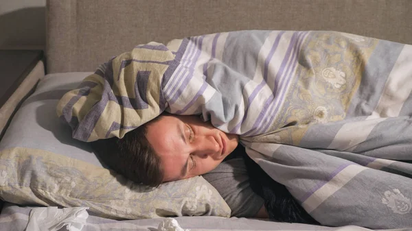 Hombre enfermo acostado debajo de una manta — Foto de Stock