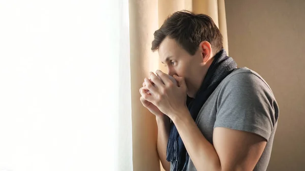 Hombre enfermo con bebida caliente cerca de la ventana — Foto de Stock