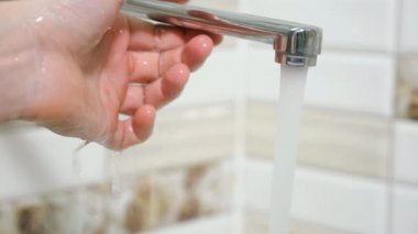 adam banyo musluk altında ellerini yıkar