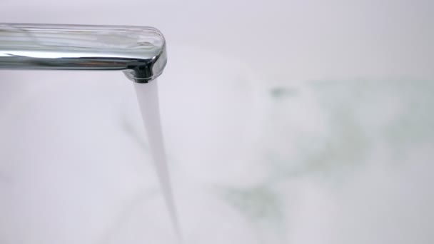 Zblízka voda vytéká z kohoutku, koupel s pěnou na pozadí — Stock video
