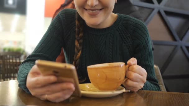 Chica desconocida utilizando aplicación en el teléfono beber café sonriendo en la cafetería — Vídeos de Stock