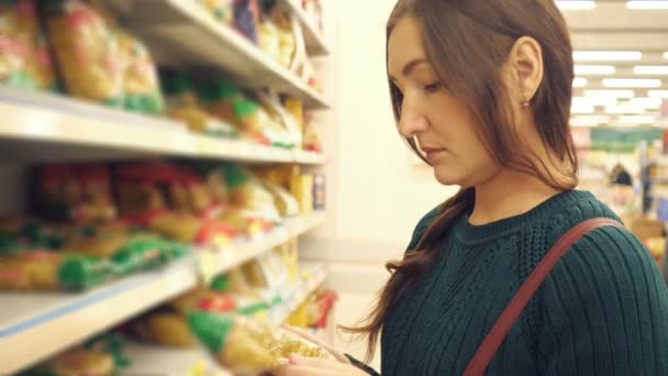 Brunett kvinna i grön tröja väljer pasta i stormarknad — Stockvideo