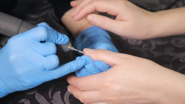 The manicurist makes manicure procedure of recovery and nail extensions on the nails of the girl in the nail salon. — Stock Video