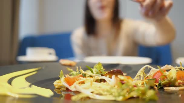 Borrado da menina estende-se a alguém elses salada. foco seletivo na salada — Vídeo de Stock