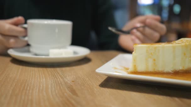 Неизвестная девушка с чашкой напитка ест торт в кафе — стоковое видео
