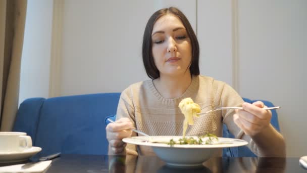 Mujer joven en un café con apetito comiendo una pasta . — Vídeos de Stock