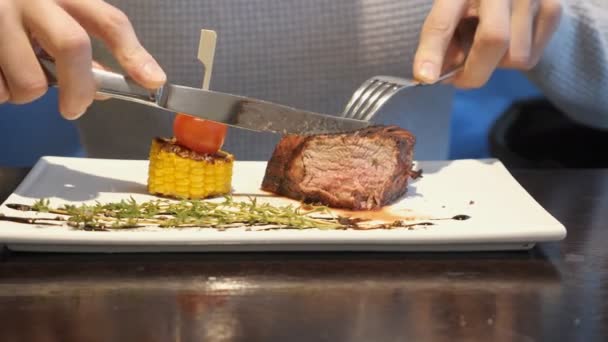 Hombre corta un pedazo de filete y come en la cafetería — Vídeos de Stock