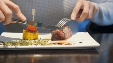 Adam biftek çatal ve bıçak ile fast food café'de akşam yeme.