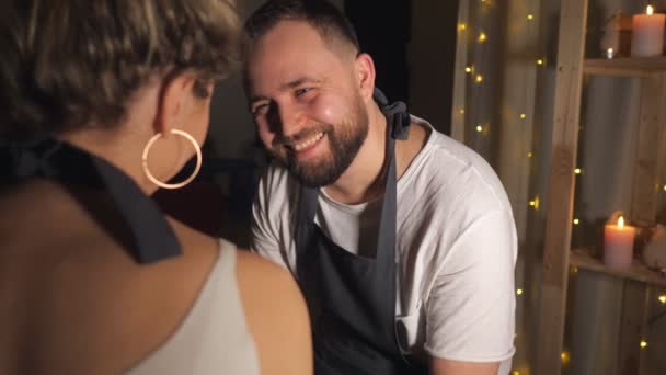 Una pareja mirándose y una chica toca la nariz del hombre con un dedo sucio en el taller de arcilla — Vídeo de stock