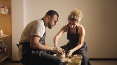 Birbirine aşık romantik bir çift çömlekçi çarkında birlikte çalışıyor ve kil çömlek yontuyorlar.,