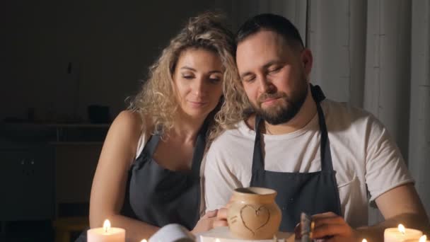 Romantický pár v rádi pracují společně v řemeslné dílny ateliéru a nakresli srdce na hliněný hrnec — Stock video