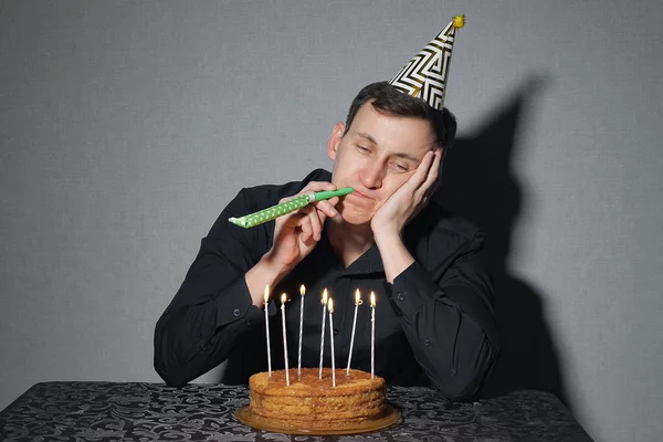 Один чоловік святкує свято, він сидить наодинці за столом з тортом і свічками — стокове фото