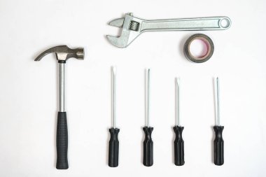 Beyaz zemin üzerinde Tornavidalar, çekiç ve anahtar üstten görünüm