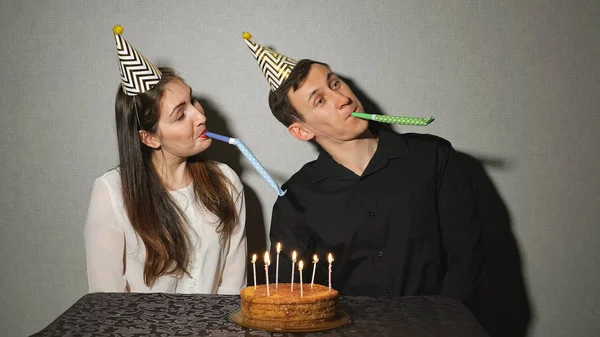 Casal sorridente celebra um feriado brincando com sopradores de festa — Fotografia de Stock